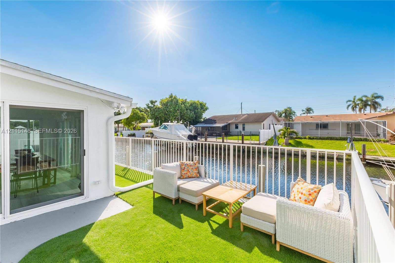 Waterfront patio featuring synthetic turf surfacing, white powder-coated railing, and direct water access