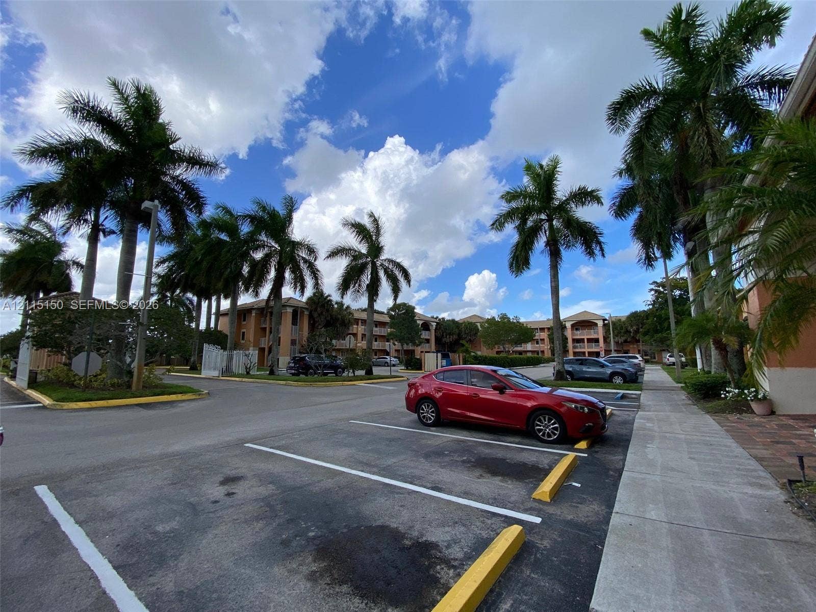 6992 SW 39th Street, #I201, Davie, Davie, FL 33314 Multi-story residential complex featuring painted stucco exterior walls, paved surface parking, and mature palm tree landscaping