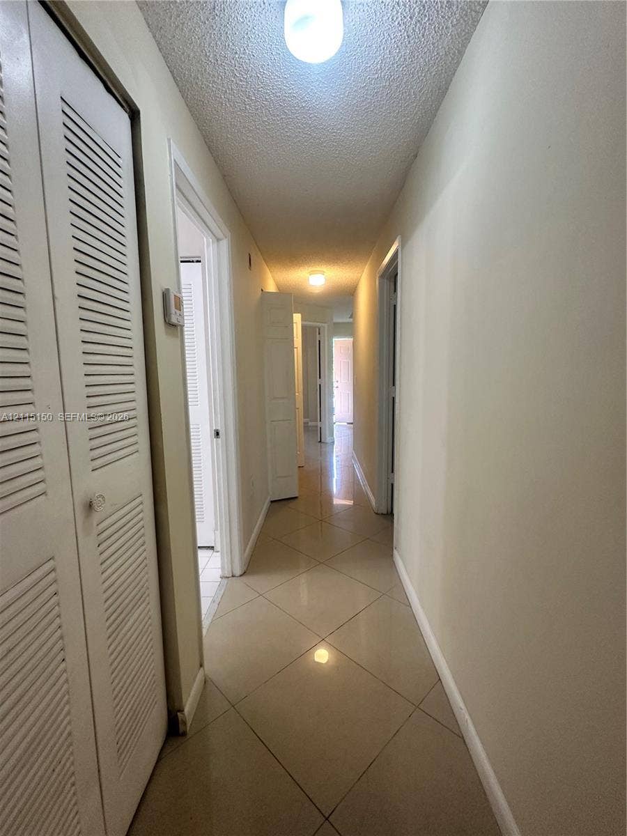 6992 SW 39th Street, #I201, Davie, Davie, FL 33314 Hallway featuring neutral large-format tile flooring and louvered-style closet doors
