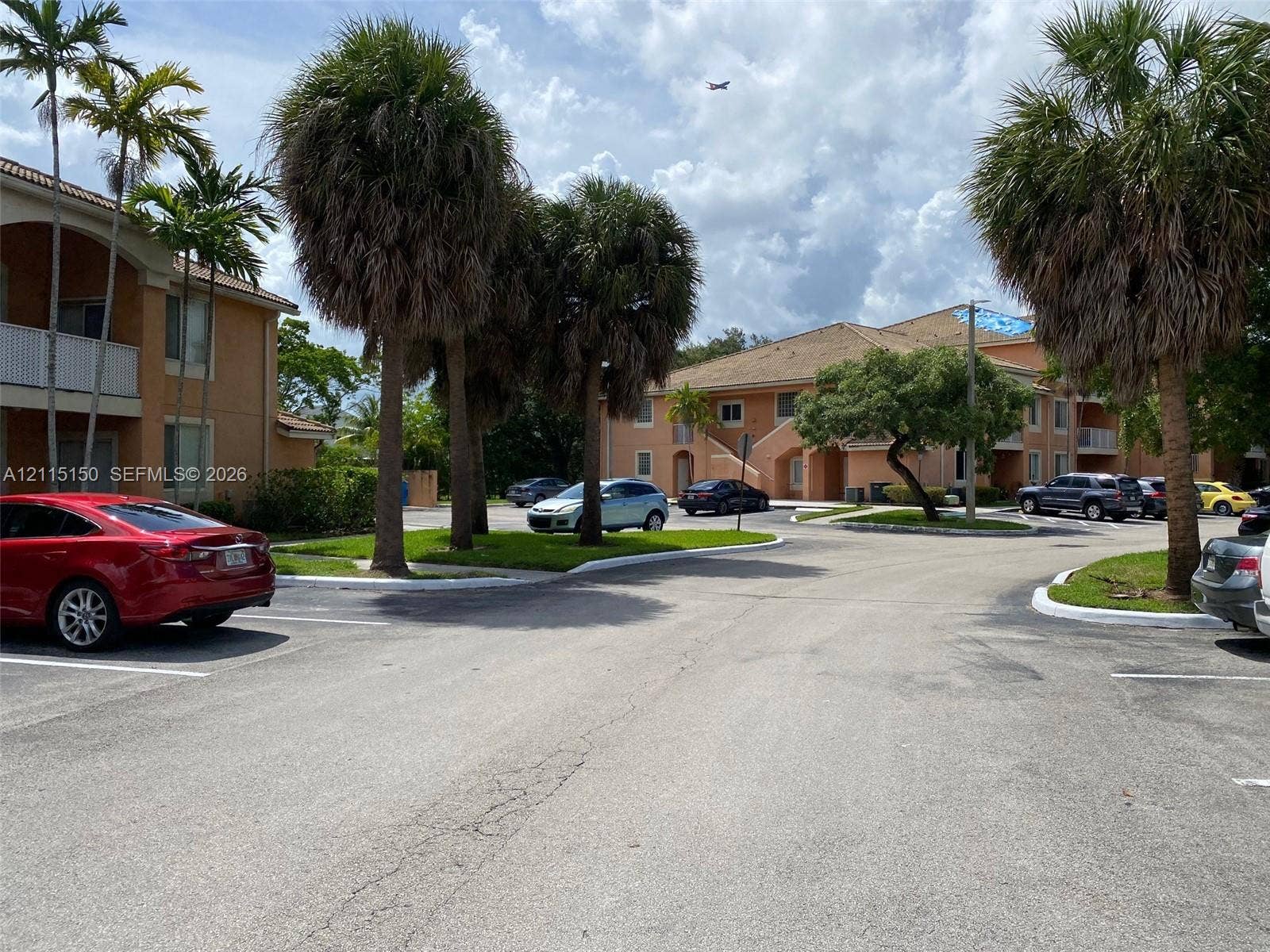 6992 SW 39th Street, #I201, Davie, Davie, FL 33314 Stucco exterior multi-story buildings featuring tiled rooflines, designated asphalt parking areas, and landscaped grounds with mature palm trees