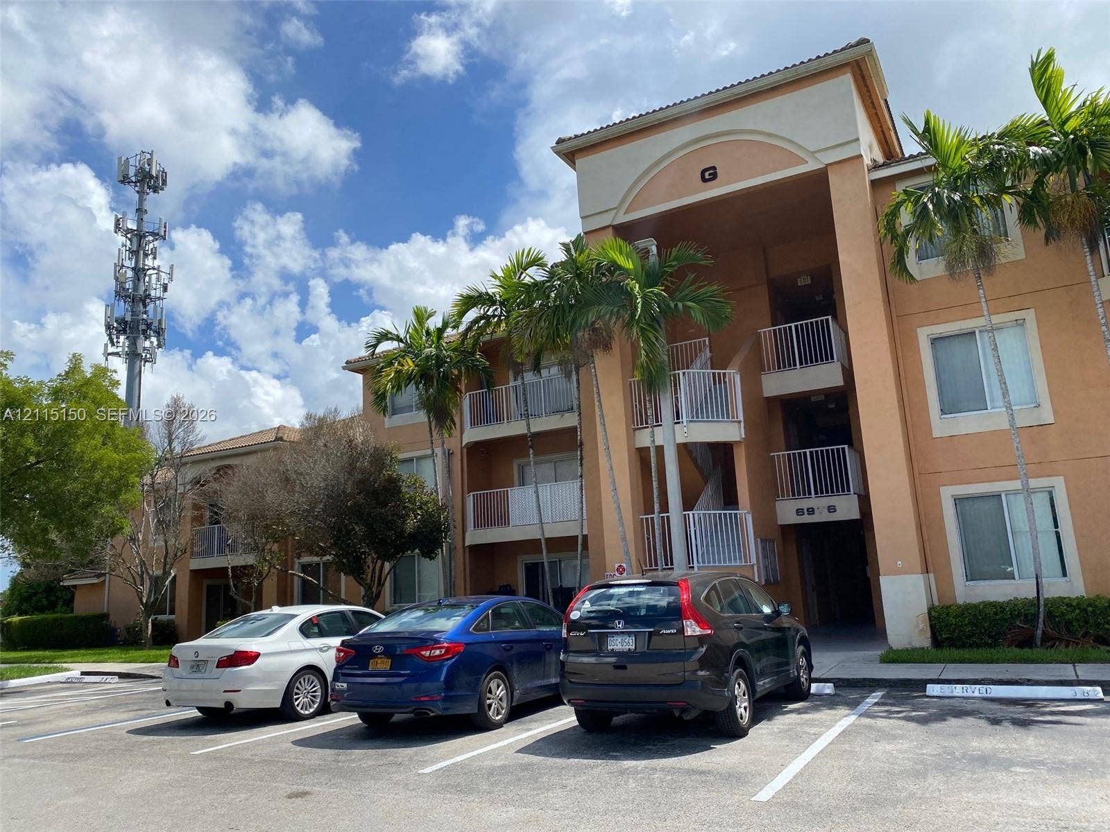 6992 SW 39th Street, #I201, Davie, Davie, FL 33314 Multi-story stucco exterior featuring arched architectural detailing, private balconies with metal railings, and mature palm landscaping