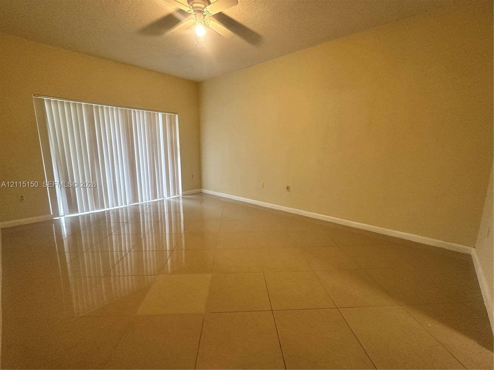 6992 SW 39th Street, #I201, Davie, Davie, FL 33314 Neutral-toned tile flooring, tall ceilings, and floor-to-ceiling vertical blinds covering a large sliding glass door