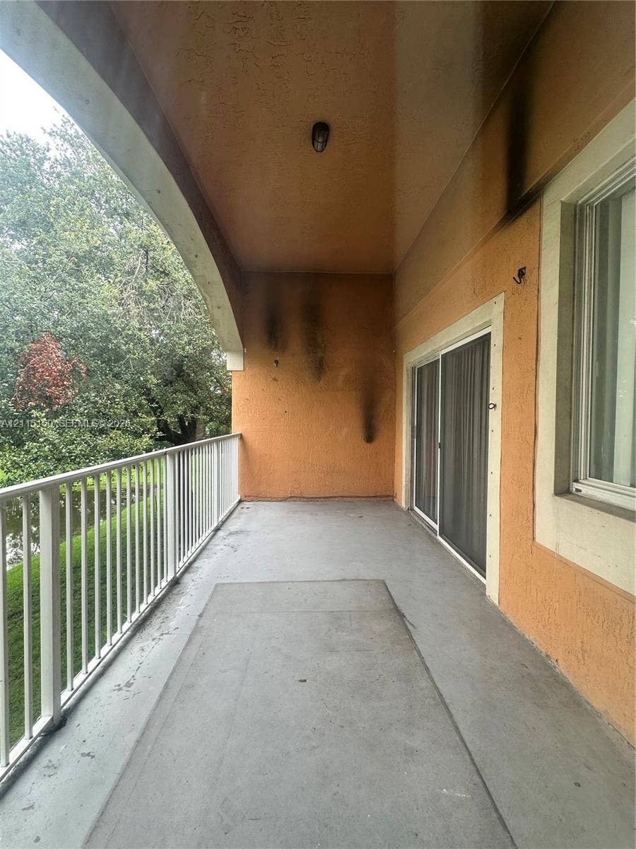 6992 SW 39th Street, #I201, Davie, Davie, FL 33314 Covered balcony featuring a white metal railing, concrete flooring, sliding glass door, and a recessed ceiling light fixture