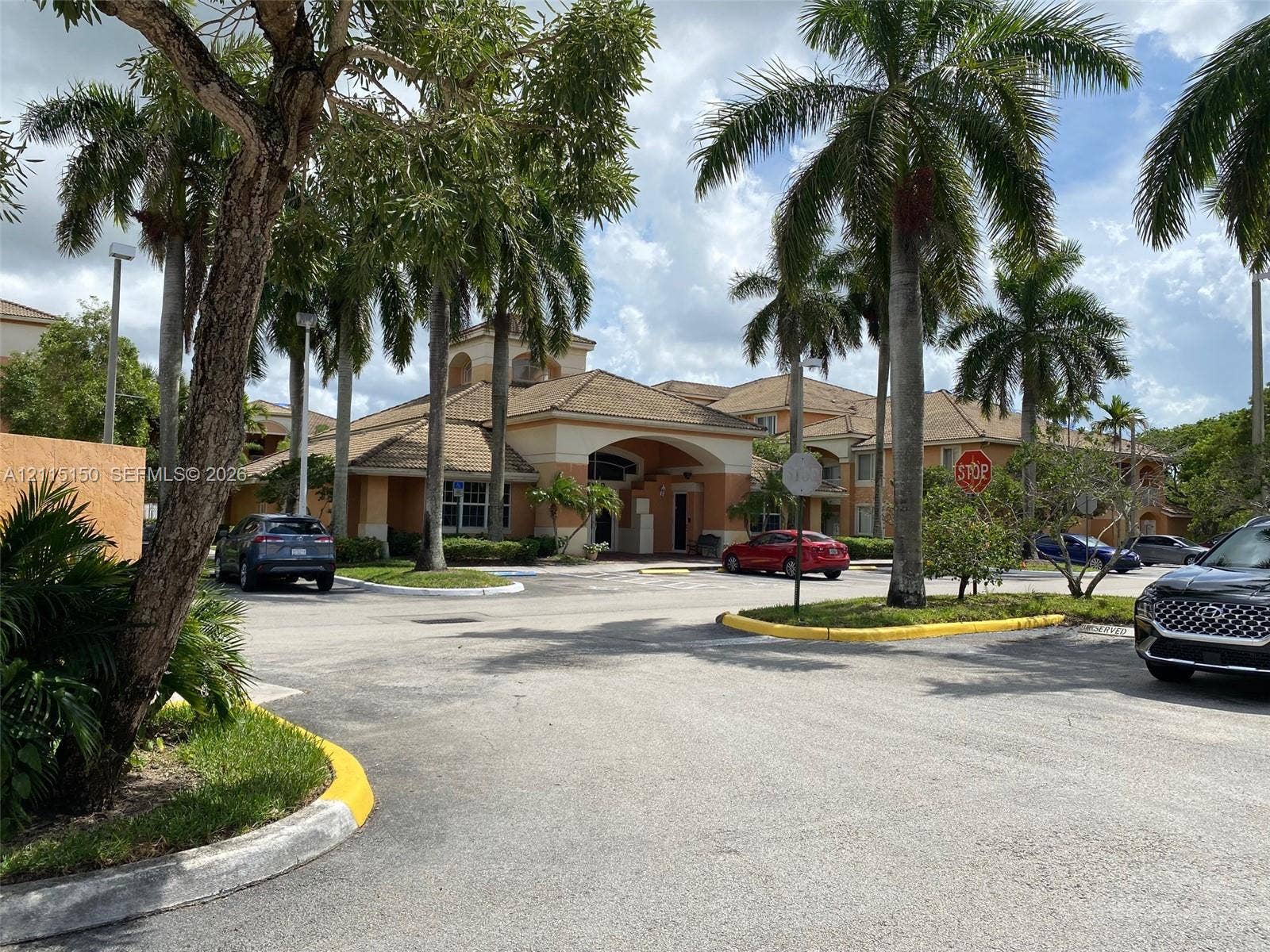 6992 SW 39th Street, #I201, Davie, Davie, FL 33314 Stucco exterior with a tiled roof, covered entryway, and mature palm trees