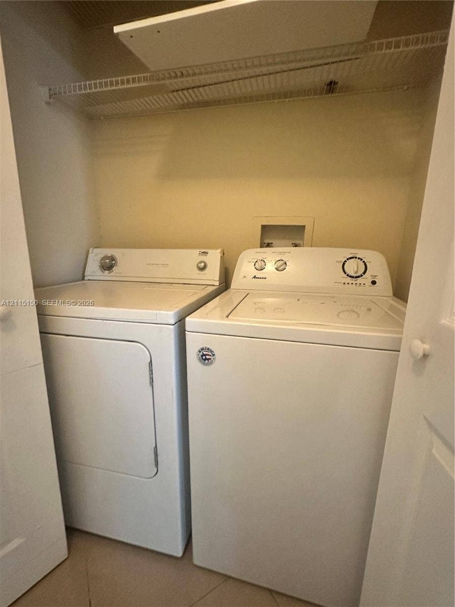 6992 SW 39th Street, #I201, Davie, Davie, FL 33314 Laundry closet featuring white top-load washer and dryer, built-in wire shelving, and neutral wall finish