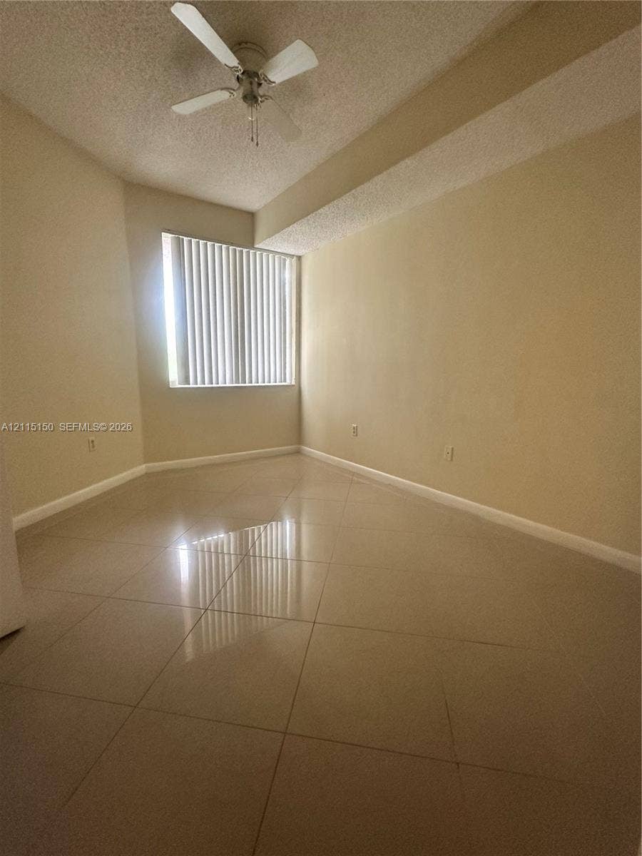 6992 SW 39th Street, #I201, Davie, Davie, FL 33314 Interior room featuring large-format tile flooring, a neutral color palette, a ceiling fan with integrated lighting, and vertical window blinds