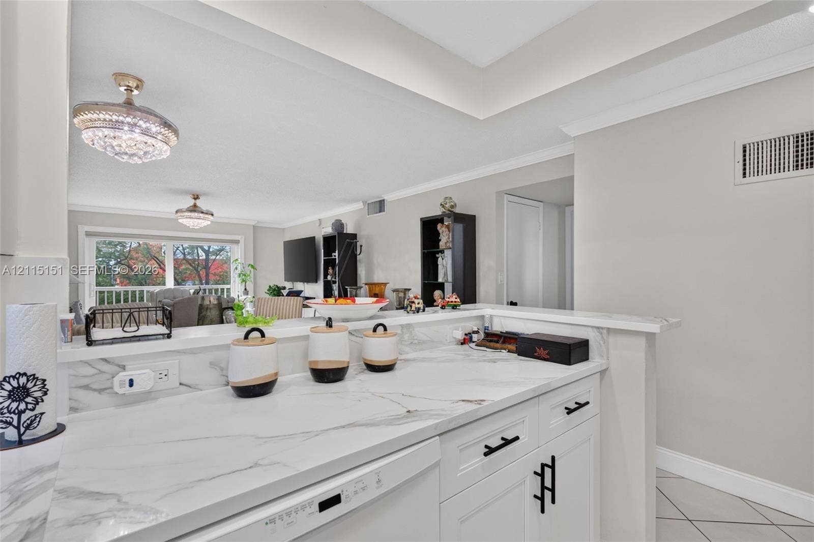 5951 NE 14th Lane, #408N, Fort Lauderdale, FL 33334 Kitchen featuring white cabinetry with matte black hardware, stone-finish countertops, ceiling crown molding, and two crystal-style pendant light fixtures