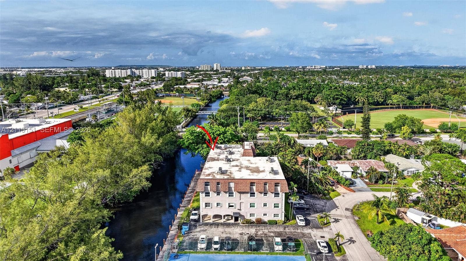 5951 NE 14th Lane, #408N, Fort Lauderdale, FL 33334 Multi-story building featuring a mansard roof, stucco exterior, paved surface parking, and a canal-side location