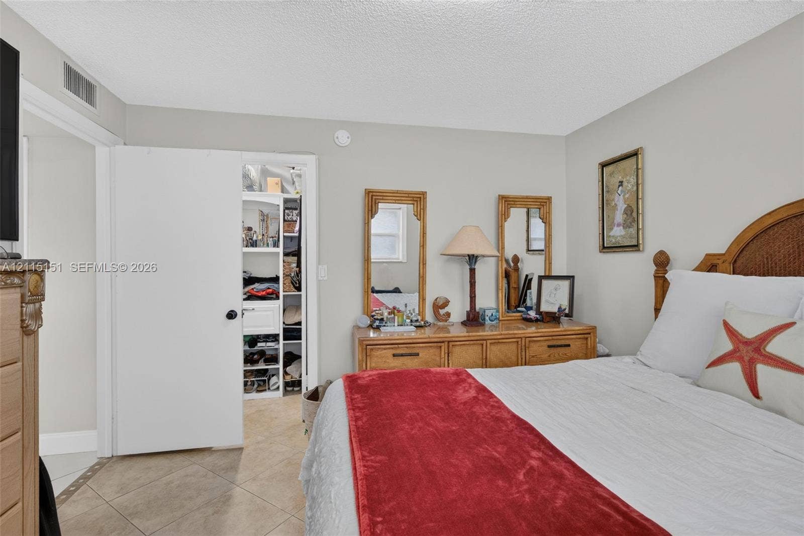 5951 NE 14th Lane, #408N, Fort Lauderdale, FL 33334 Bedroom featuring light-toned neutral wall paint, tile flooring laid on a diagonal pattern, and a built-in closet with integrated shelving