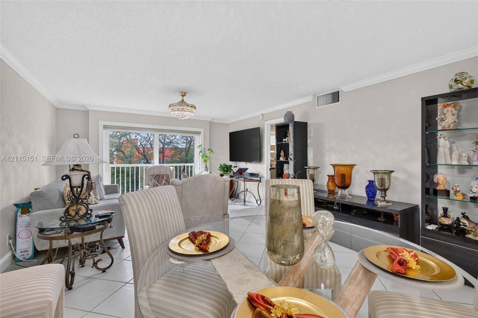 5951 NE 14th Lane, #408N, Fort Lauderdale, FL 33334 Neutral-toned interior featuring large-format diagonal tile flooring, crown molding, a crystal-style chandelier, and sliding glass doors with access to an outdoor balcony