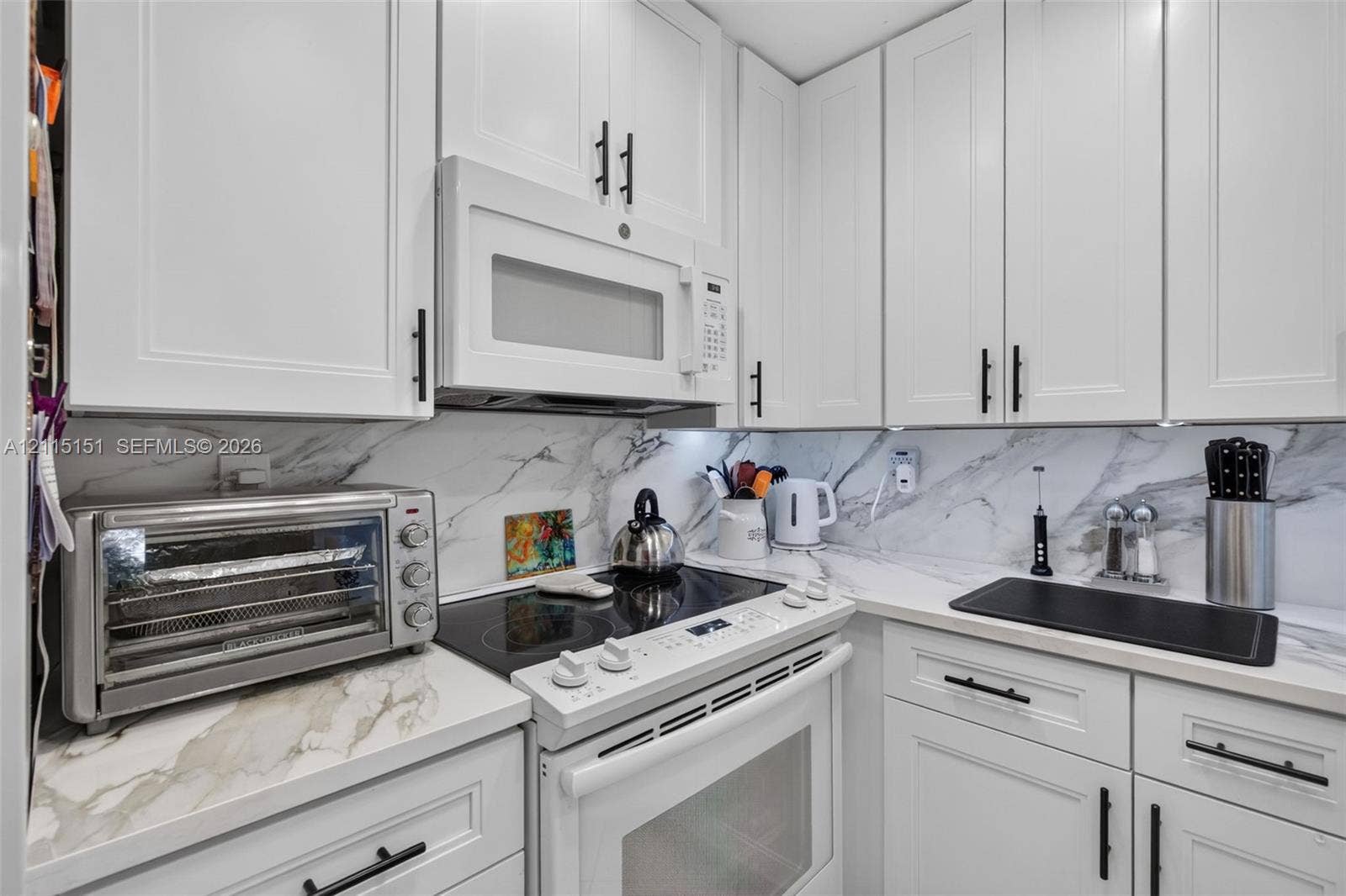 5951 NE 14th Lane, #408N, Fort Lauderdale, FL 33334 White shaker-style cabinetry with matte black hardware, stone-patterned backsplash, and matching stone-patterned countertops