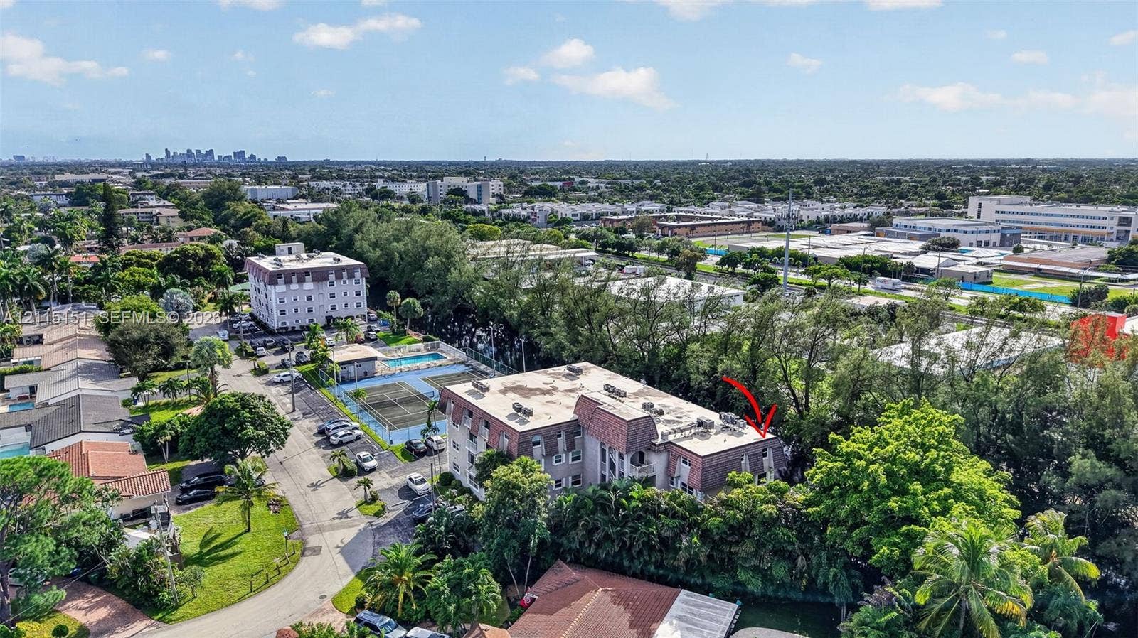5951 NE 14th Lane, #408N, Fort Lauderdale, FL 33334 Aerial perspective of a multi-story residential building featuring a flat roofline, paved parking area, on-site tennis court, and outdoor swimming pool