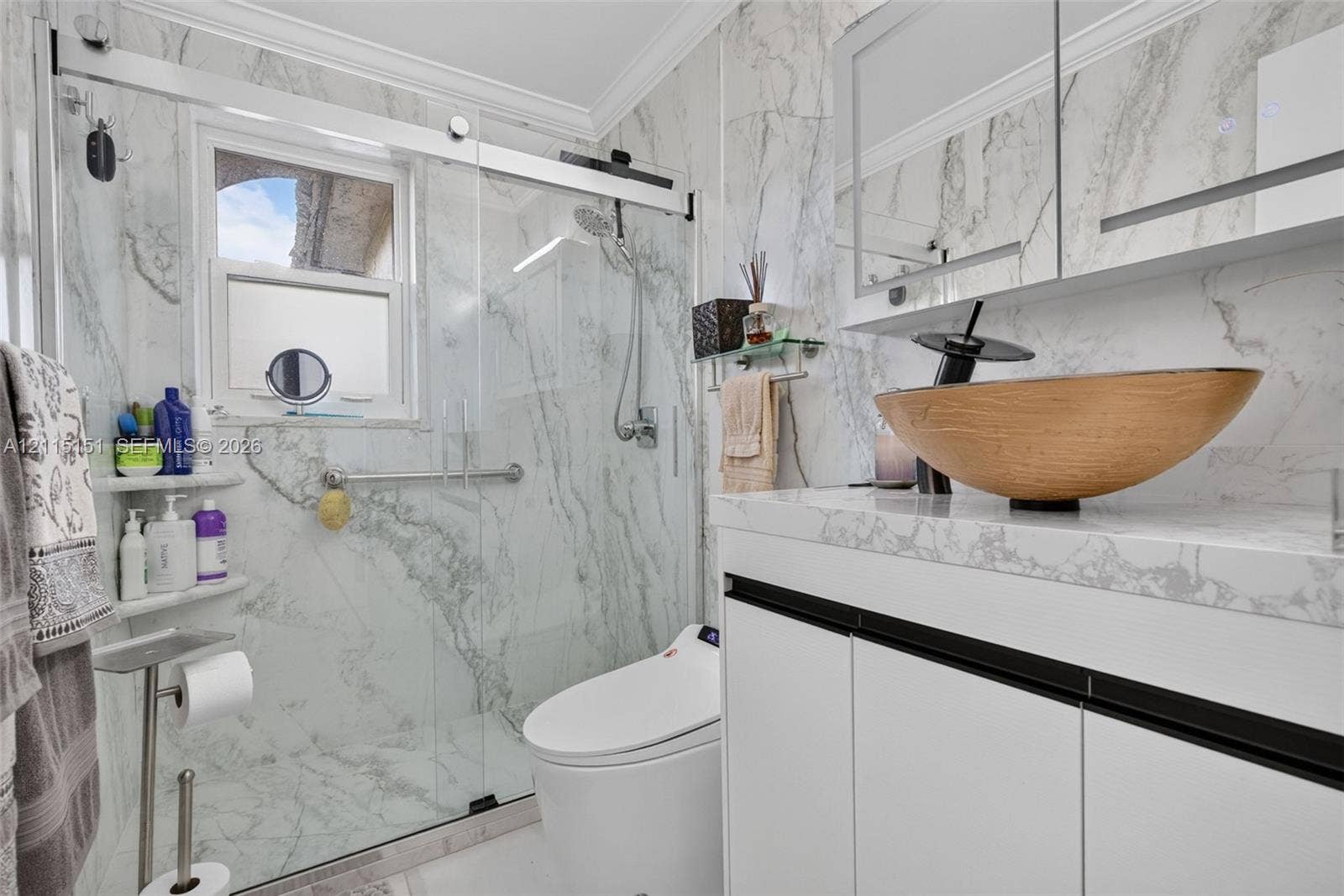 5951 NE 14th Lane, #408N, Fort Lauderdale, FL 33334 Bathroom featuring full-height stone-finish wall tile, frameless glass shower enclosure, vanity with stone-finish countertop, vessel sink with matte black faucet, and built-in medicine cabinet