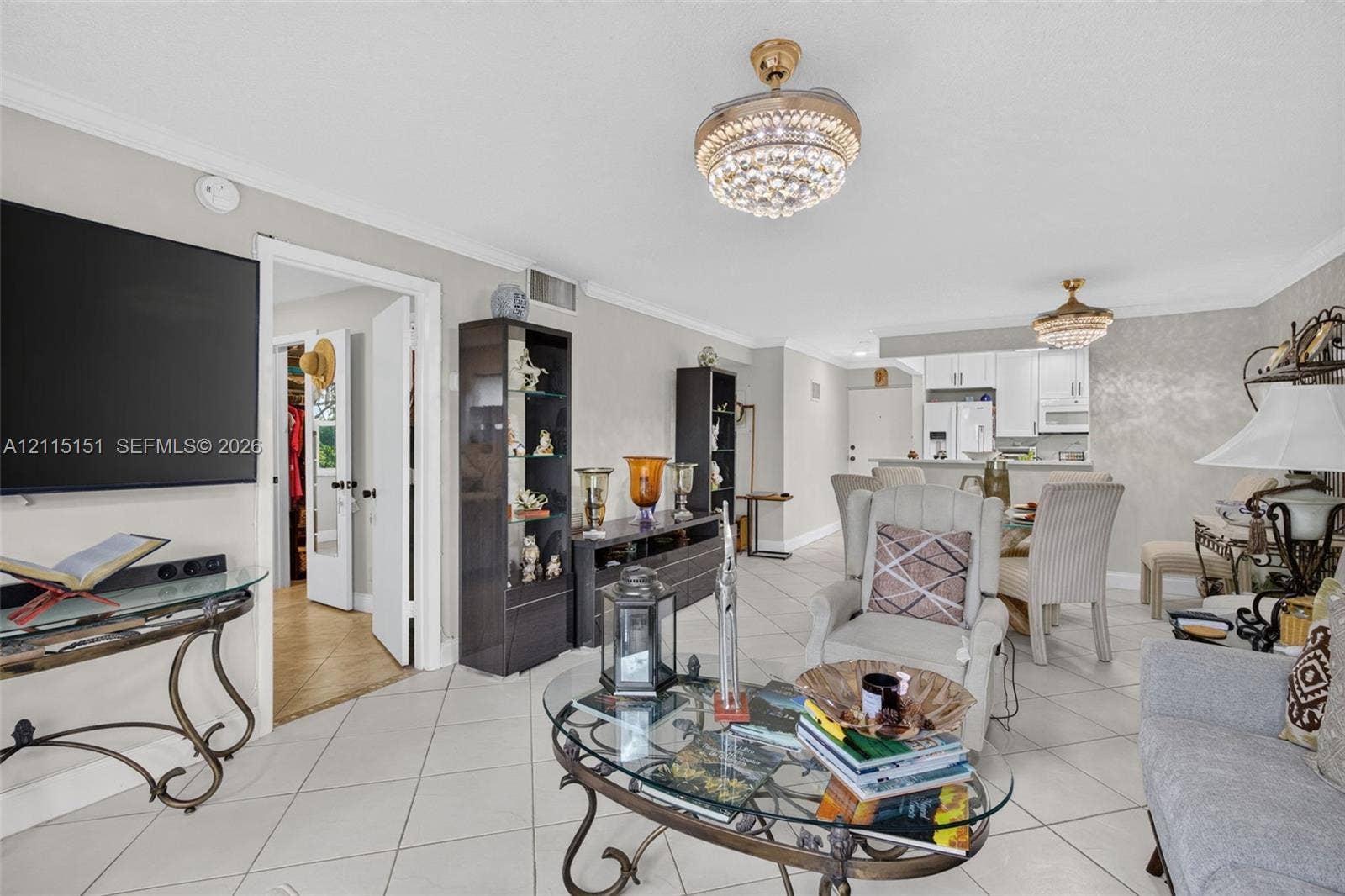 5951 NE 14th Lane, #408N, Fort Lauderdale, FL 33334 Open-concept interior featuring oversized tile flooring, crown molding, dual crystal-accented chandelier ceiling fans, and textured wall finish
