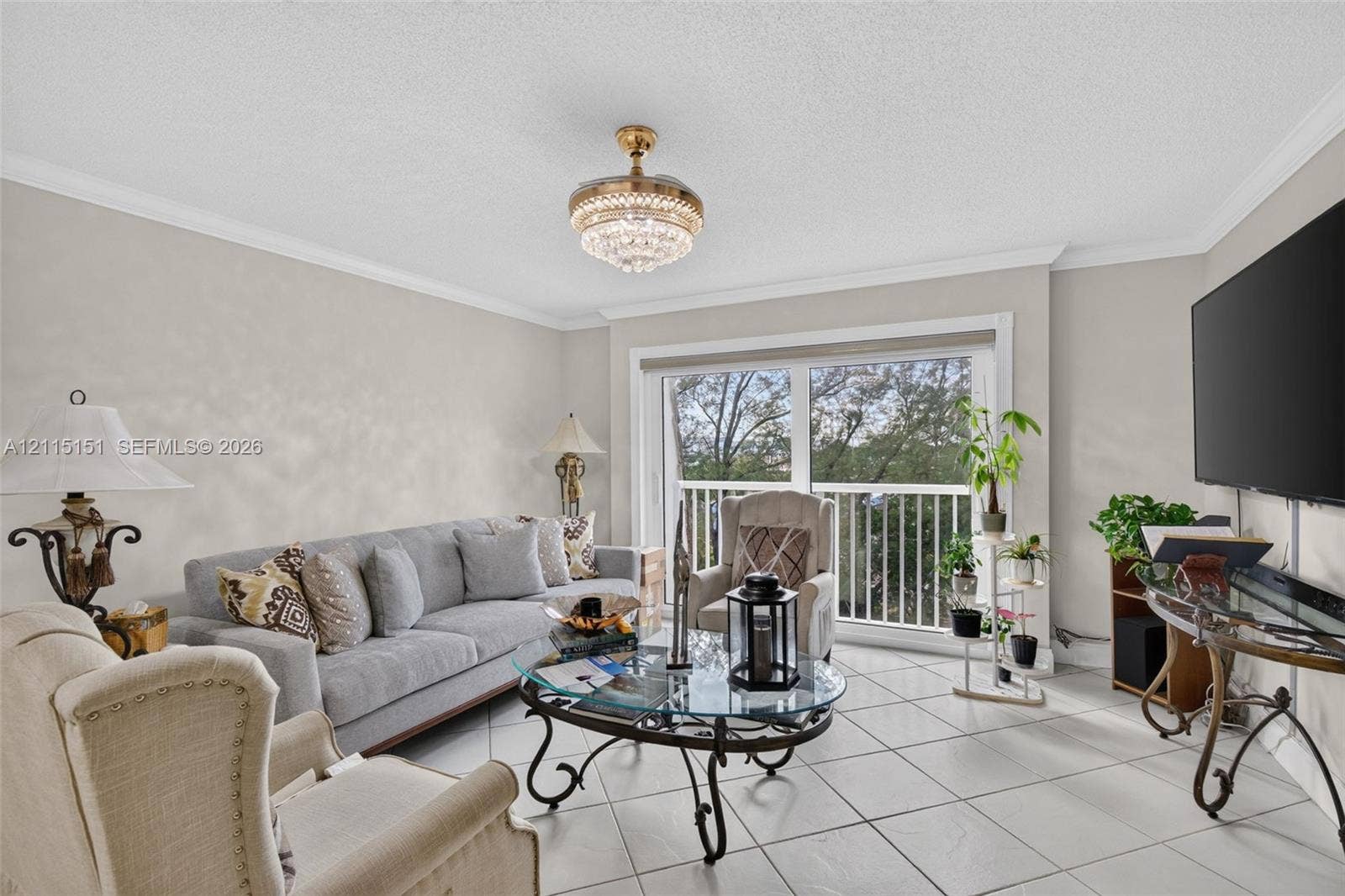 5951 NE 14th Lane, #408N, Fort Lauderdale, FL 33334 Living area featuring tile flooring, crown molding, a crystal-accented chandelier, and a sliding glass door with a balcony railing