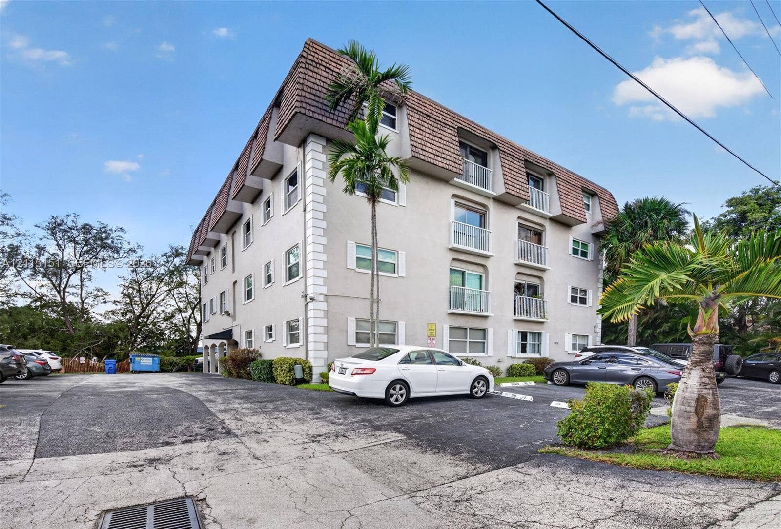 5951 NE 14th Lane, #408N, Fort Lauderdale, FL 33334 Multi-story building exterior featuring a mansard roofline, stucco facade with corner quoins, and multiple private balconies with metal railings