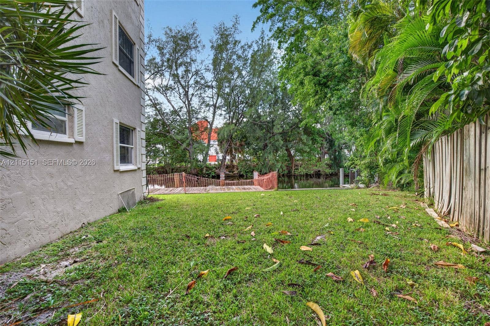 5951 NE 14th Lane, #408N, Fort Lauderdale, FL 33334 Stucco exterior, expansive lawn, mature foliage, wooden dock, and waterfront bulkhead