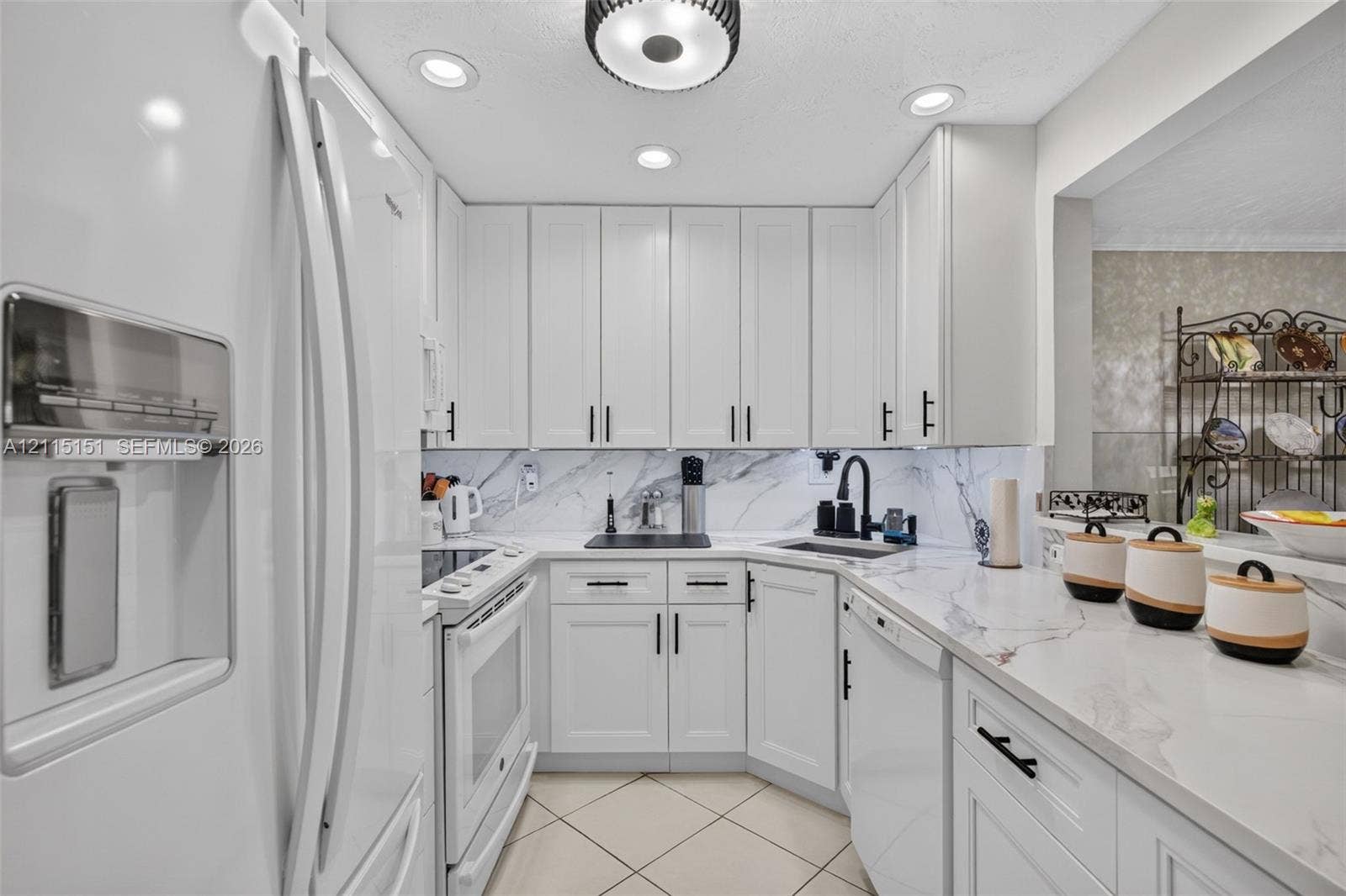 5951 NE 14th Lane, #408N, Fort Lauderdale, FL 33334 Kitchen featuring white shaker-style cabinetry, stone-finish countertops, full-height stone backsplash, matte black hardware, and recessed lighting