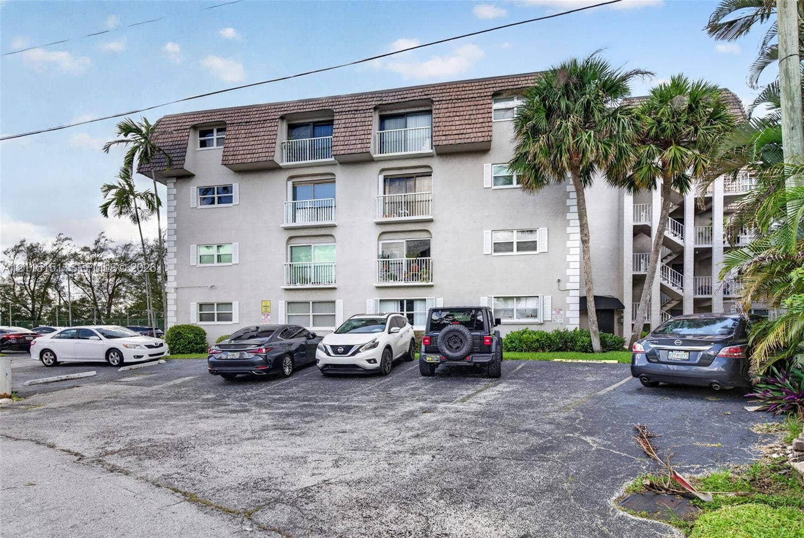5951 NE 14th Lane, #408N, Fort Lauderdale, FL 33334 Multi-story exterior featuring a textured facade, mansard-style roofline, and private balconies with metal railings