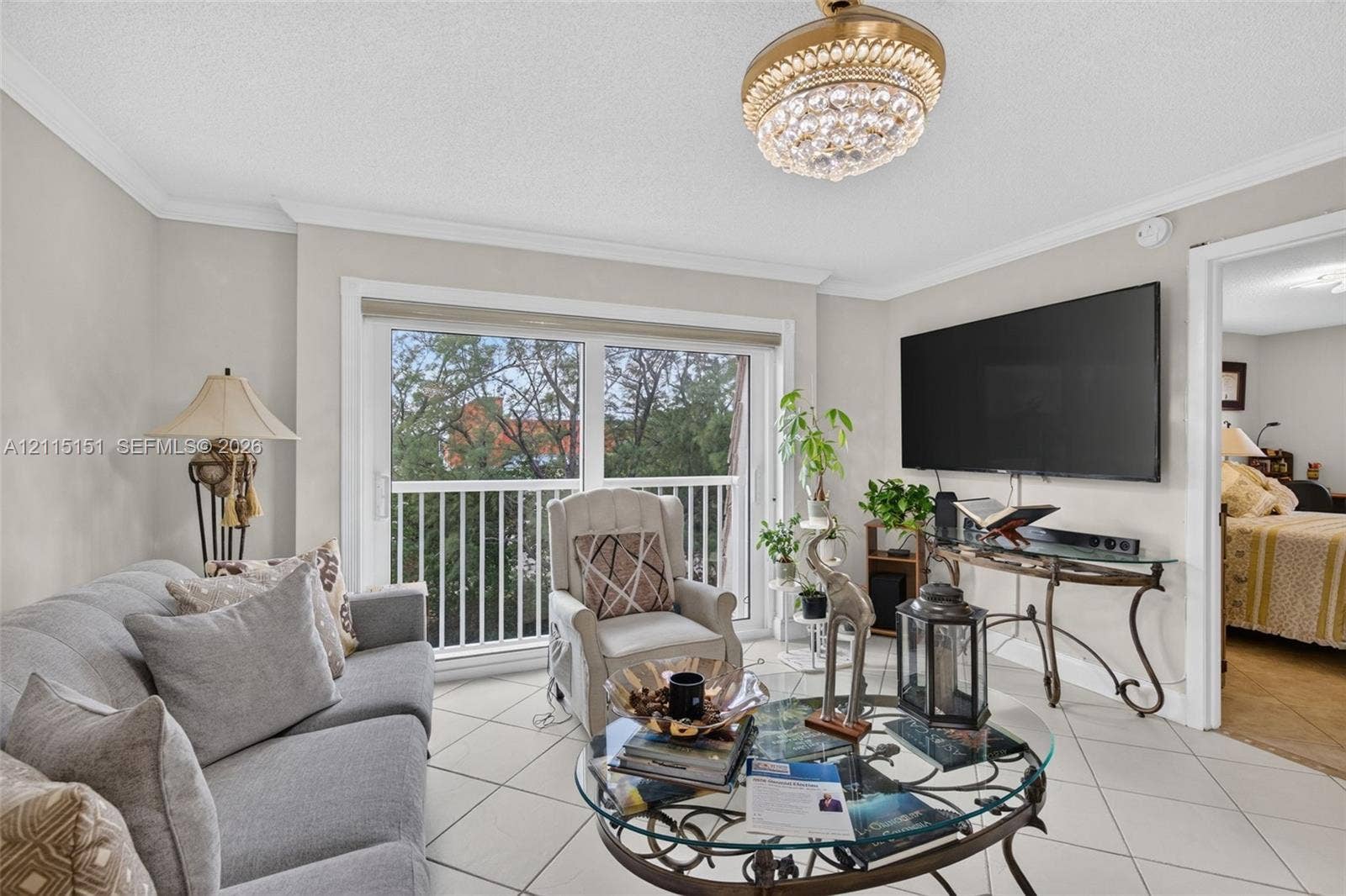 5951 NE 14th Lane, #408N, Fort Lauderdale, FL 33334 Ceramic tile flooring, crown molding, decorative crystal chandelier, and glass sliding door providing access to a private balcony