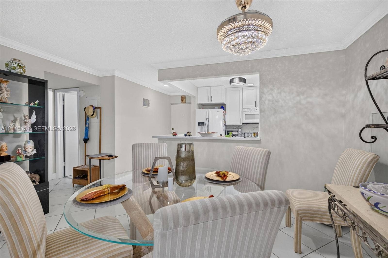 5951 NE 14th Lane, #408N, Fort Lauderdale, FL 33334 Open concept floor plan featuring a kitchen pass-through window with a breakfast bar, white cabinetry, tile flooring, and a crystal-accented ceiling light fixture