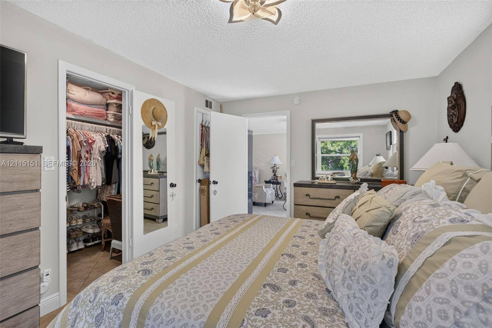 5951 NE 14th Lane, #408N, Fort Lauderdale, FL 33334 Bedroom featuring a multi-pane window, closet with a mirrored door, interior doorway, and a ceiling-mounted light fixture