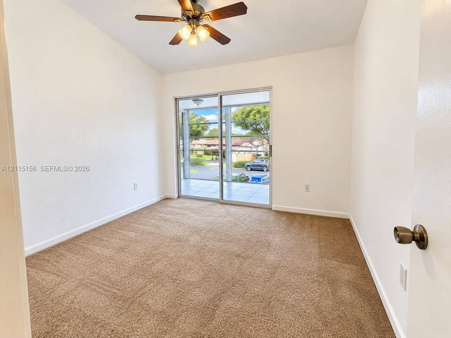 4800 NW 102nd Avenue, #201-10, Doral, Doral, FL 33178 Neutral-toned wall-to-wall carpeting, vaulted ceilings, multi-blade ceiling fan with integrated lighting, and sliding glass doors with access to an exterior patio