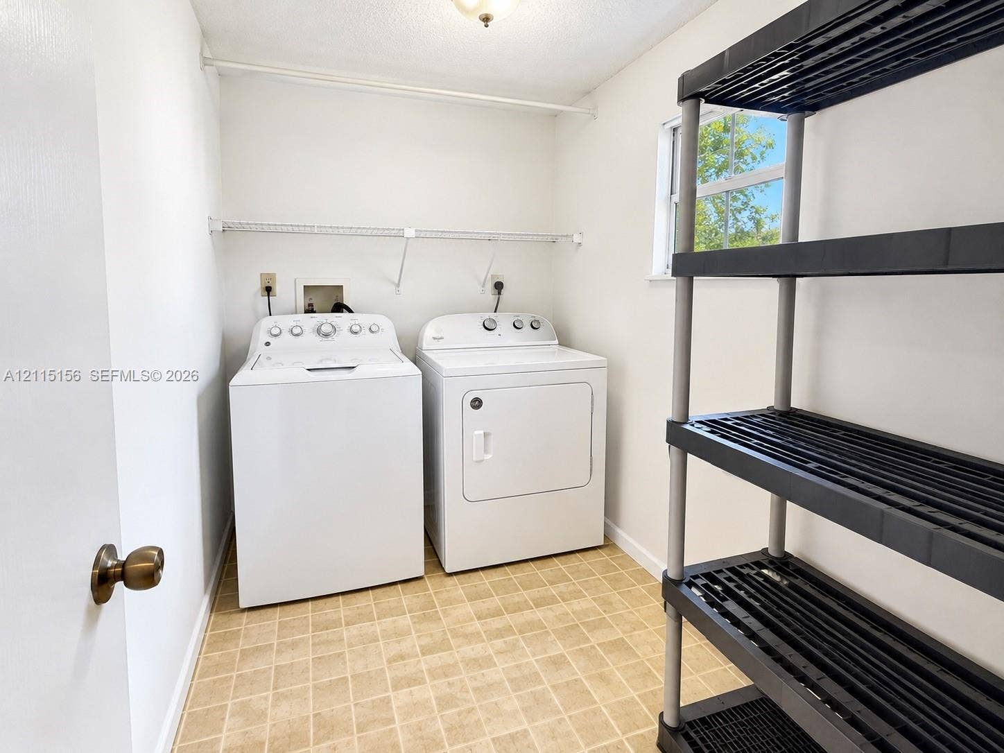 4800 NW 102nd Avenue, #201-10, Doral, Doral, FL 33178 Laundry room featuring vinyl tile flooring, a window providing natural light, and an installed wire shelving unit