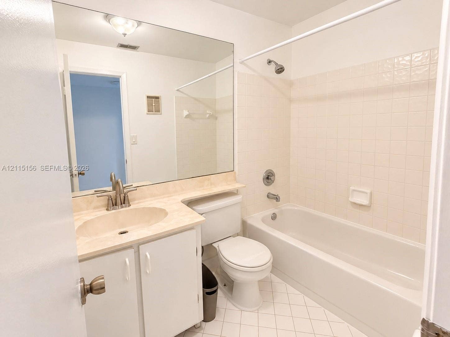 4800 NW 102nd Avenue, #201-10, Doral, Doral, FL 33178 Full-width vanity with an integrated oval basin and stone-finish countertop, large wall-mounted mirror, combination tub and shower with tile surround, and diamond-pattern floor tile
