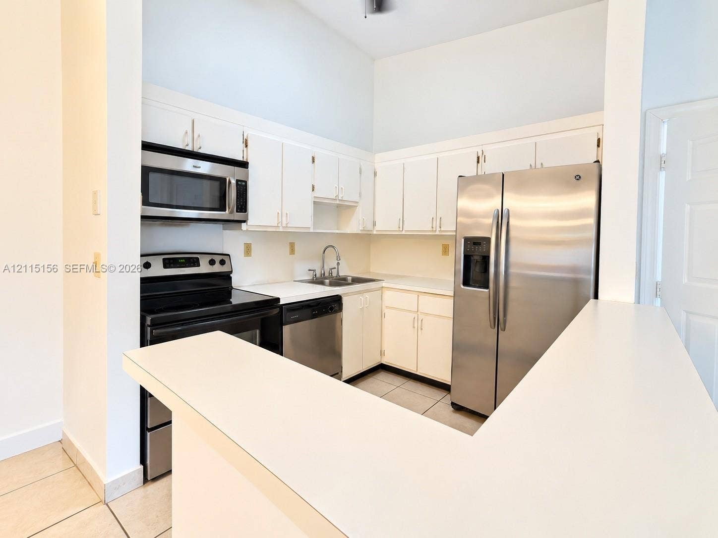 4800 NW 102nd Avenue, #201-10, Doral, Doral, FL 33178 Kitchen featuring white cabinetry, solid surface countertops, stainless steel refrigerator, built-in microwave, and tile flooring