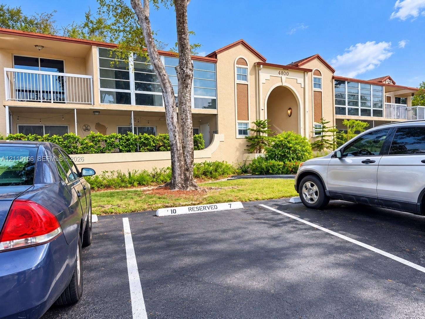 4800 NW 102nd Avenue, #201-10, Doral, Doral, FL 33178 Stucco exterior featuring second-level private balconies with railings, multi-pane window configurations, and a prominent arched entryway