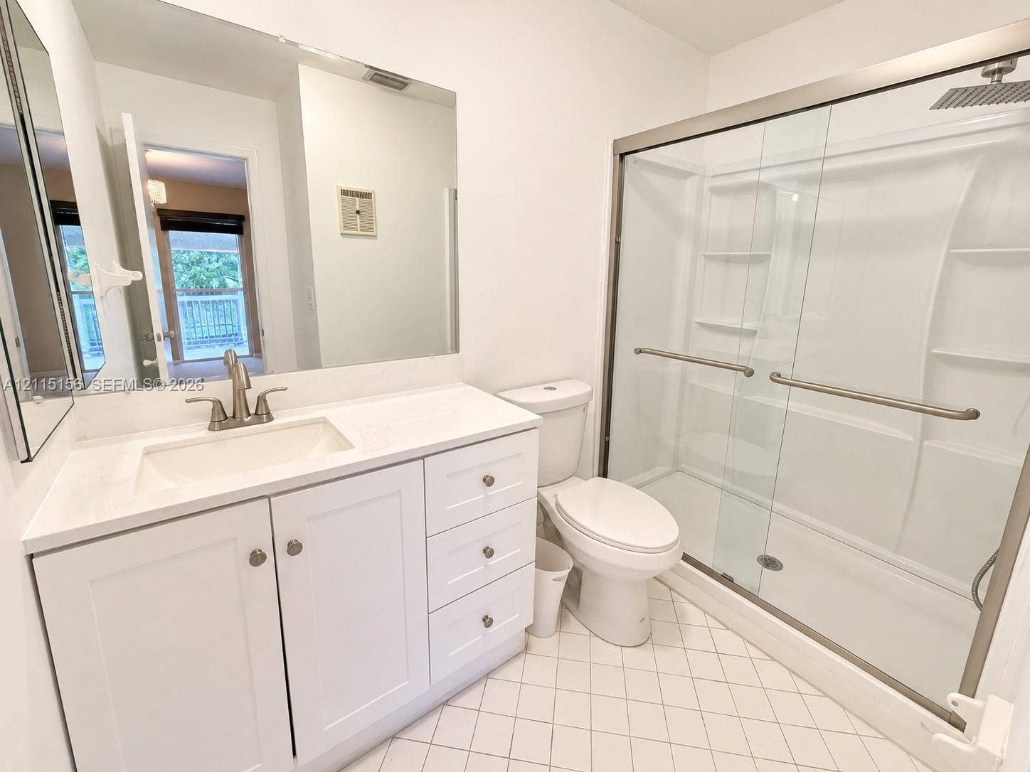 4800 NW 102nd Avenue, #201-10, Doral, Doral, FL 33178 Bathroom featuring white cabinetry, solid-surface countertop, full-width wall mirror, shower with glass sliding doors and integrated shelving, and tiled flooring