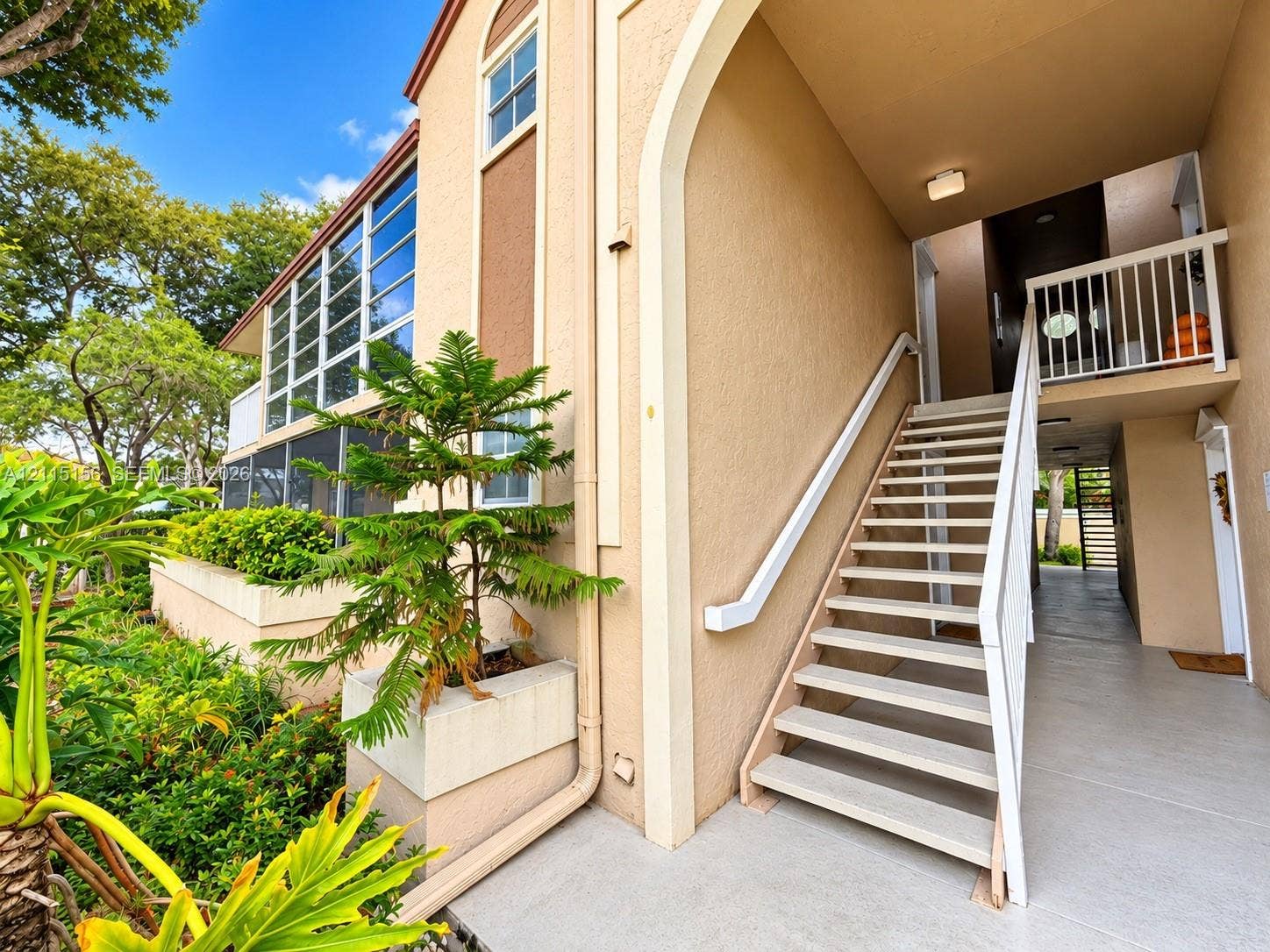 4800 NW 102nd Avenue, #201-10, Doral, Doral, FL 33178 Stucco exterior featuring an arched entryway, multi-story open-air staircase, built-in concrete planter, and oversized windows