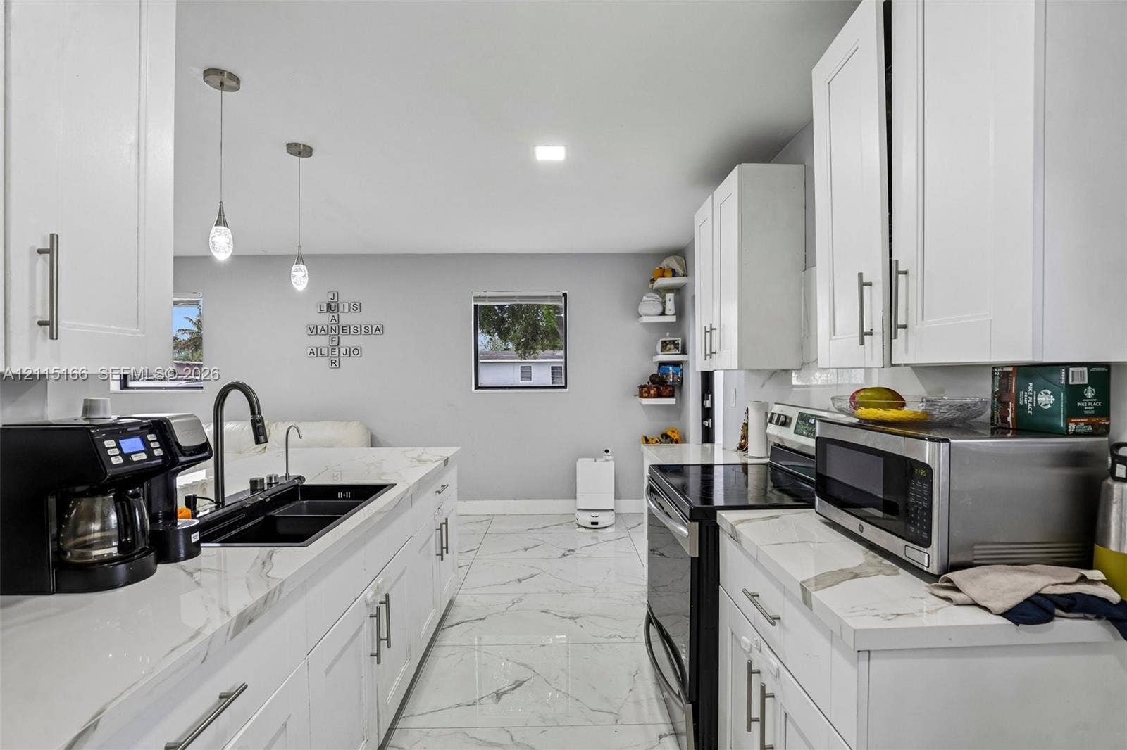 1421 N 68th Terrace, Hollywood, FL 33024 Kitchen featuring white shaker-style cabinetry, stone-finish countertops, large-format tile flooring, a dual-basin undermount sink with a matte black faucet, and pendant lighting