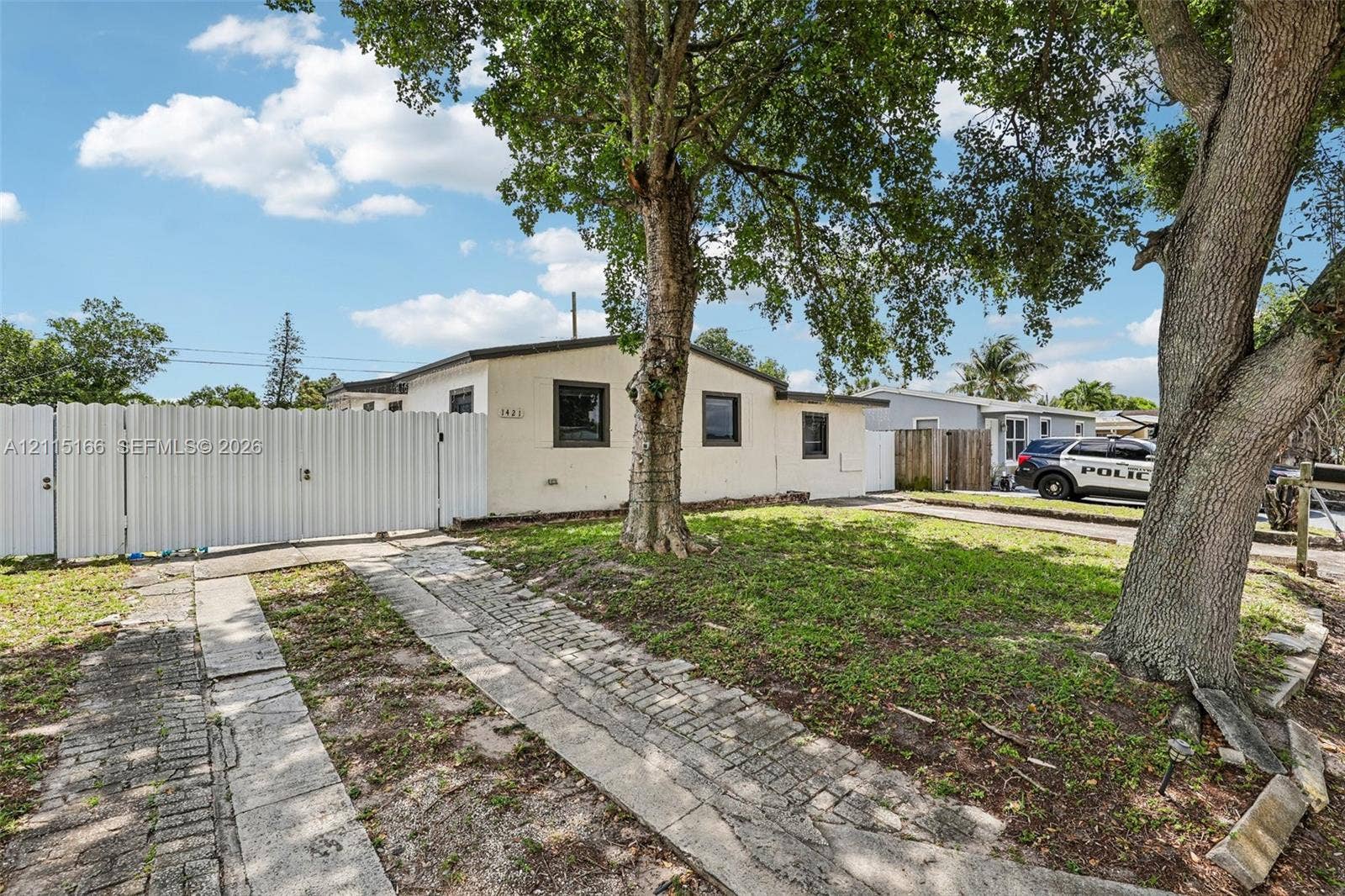 1421 N 68th Terrace, Hollywood, FL 33024 Single-story stucco exterior featuring a gated entry, paver driveway, and mature landscaping