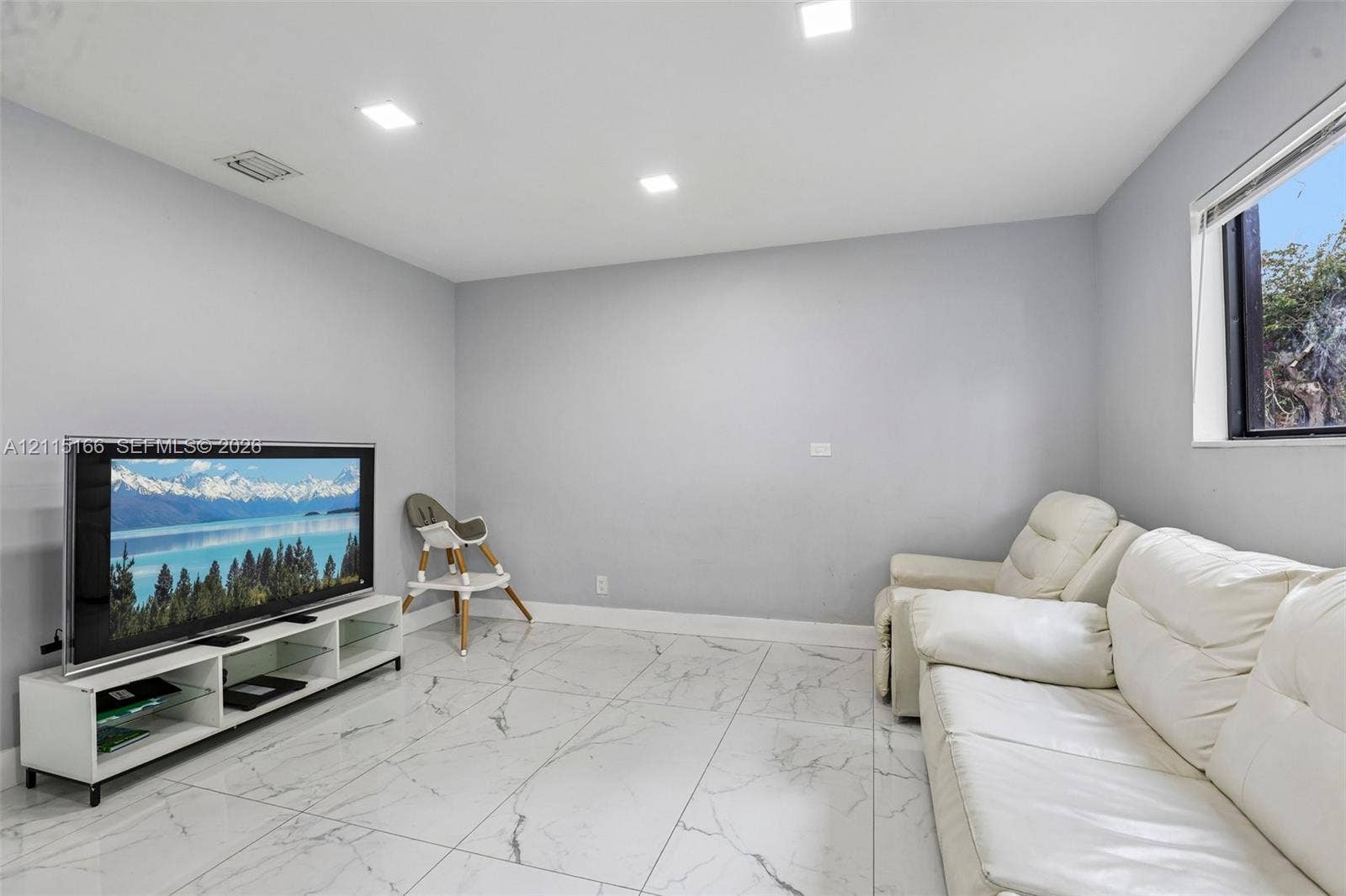 1421 N 68th Terrace, Hollywood, FL 33024 Room featuring large-format porcelain tile flooring with veining, recessed LED lighting, and a window with a white frame