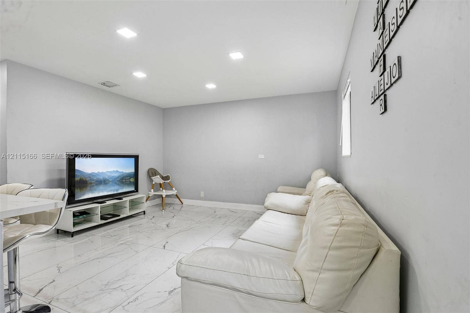 1421 N 68th Terrace, Hollywood, FL 33024 Neutral-toned interior space featuring large-format stone-finish flooring with veining, recessed LED lighting, and smooth wall finishes