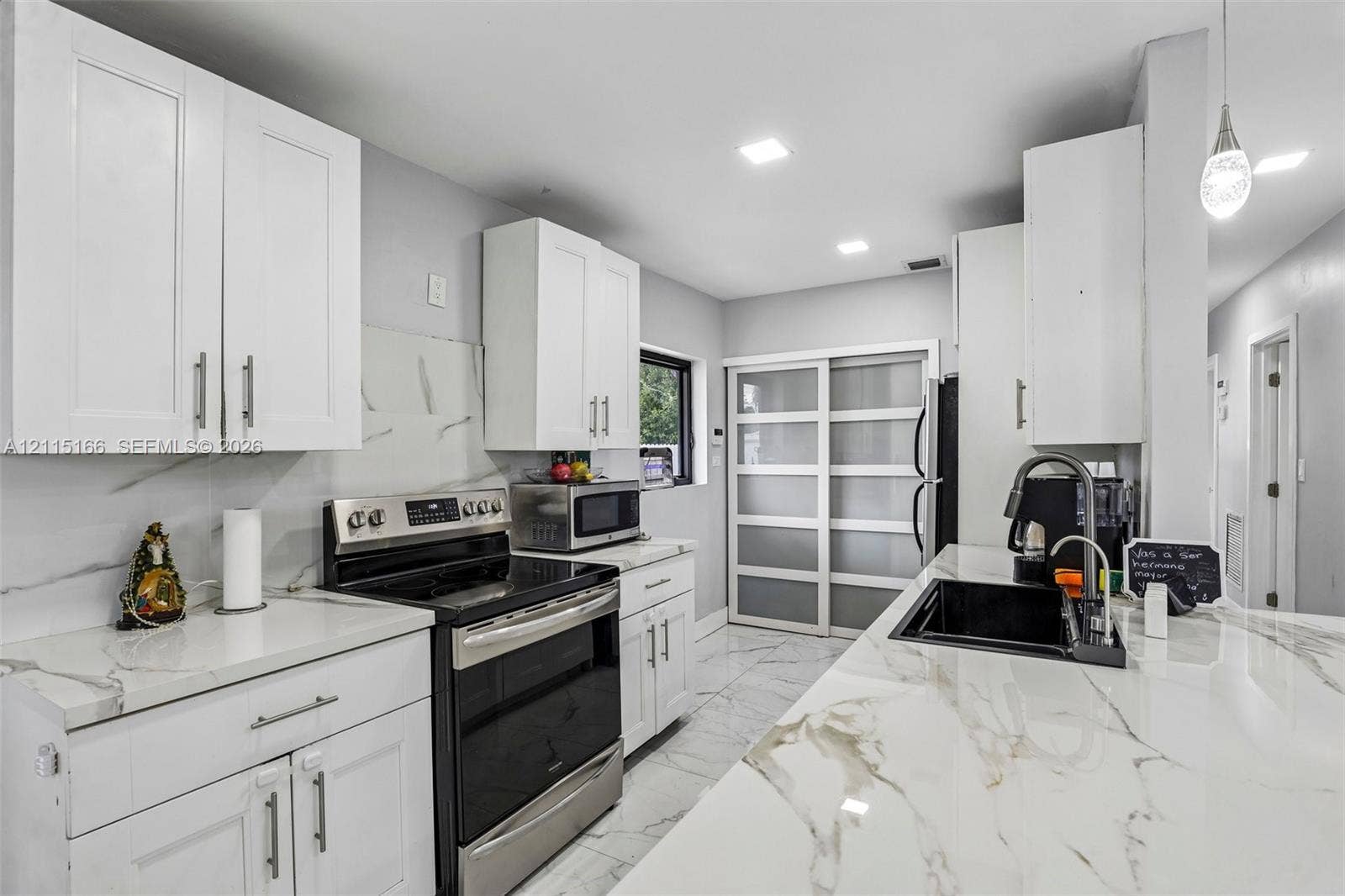 1421 N 68th Terrace, Hollywood, FL 33024 Kitchen featuring white shaker-style cabinetry, white countertops with grey veining, a stainless steel range, a black undermount sink with a pull-down faucet, and large-format tile flooring