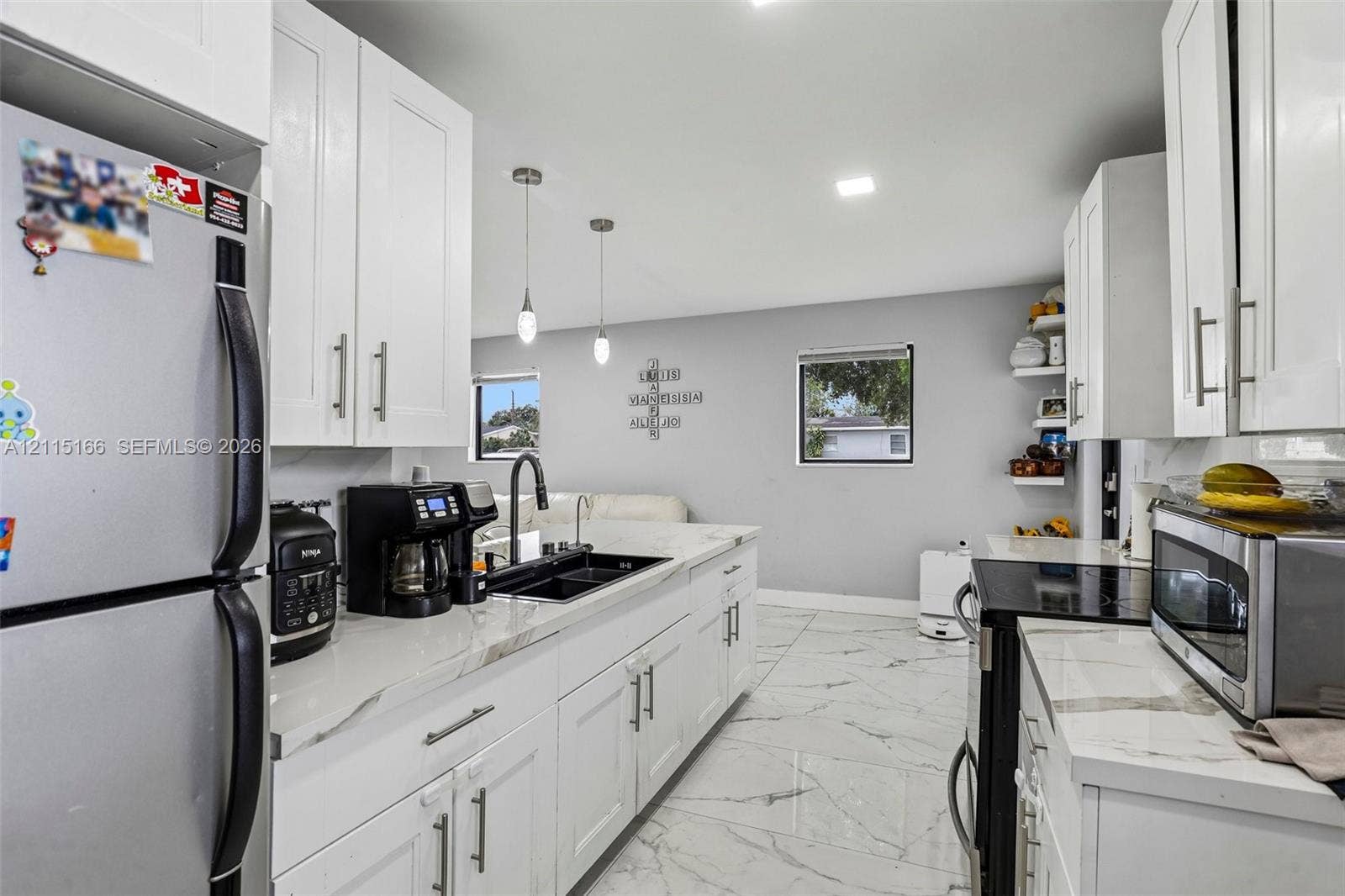 1421 N 68th Terrace, Hollywood, FL 33024 Kitchen featuring white shaker-style cabinetry, stone-patterned countertops, dual-basin undermount sink with a gooseneck faucet, large-format tile flooring, and glass pendant lighting