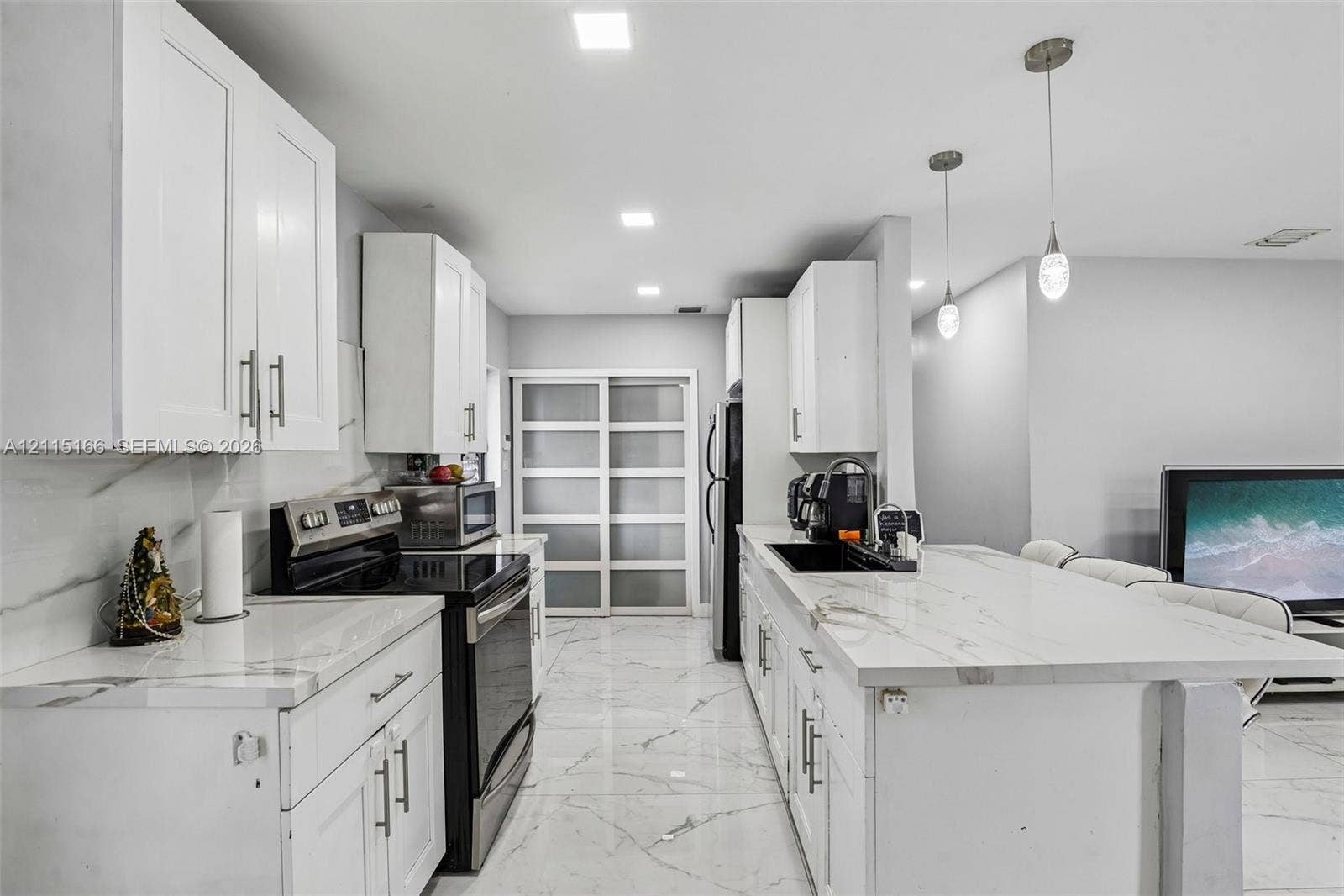 1421 N 68th Terrace, Hollywood, FL 33024 Kitchen featuring white shaker-style cabinetry, white countertops with grey veining, large-format tile flooring, recessed lighting, and dual pendant light fixtures