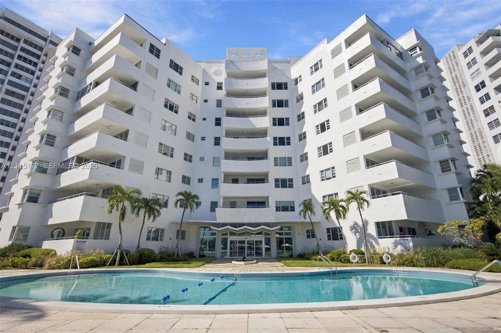 16 Island Avenue, #5C, Miami Beach, FL 33139 Mid-rise residential building featuring stacked private balconies, a ground-level swimming pool, and stone-paved pool deck