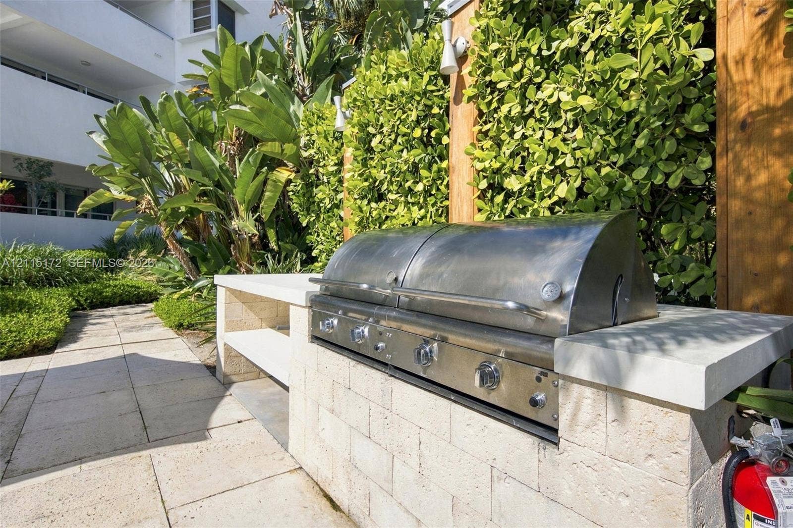 16 Island Avenue, #5C, Miami Beach, FL 33139 Outdoor kitchen featuring a built-in stainless steel grill, natural stone block counter, and paver hardscaping