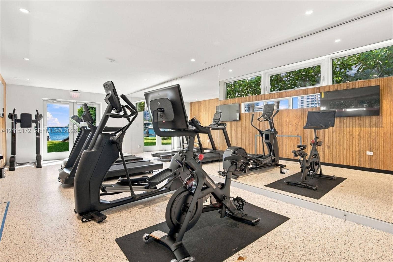 16 Island Avenue, #5C, Miami Beach, FL 33139 Fitness area featuring full-wall mirrors, recessed lighting, wood-slat accent wall cladding, and floor-to-ceiling glass doors providing natural light