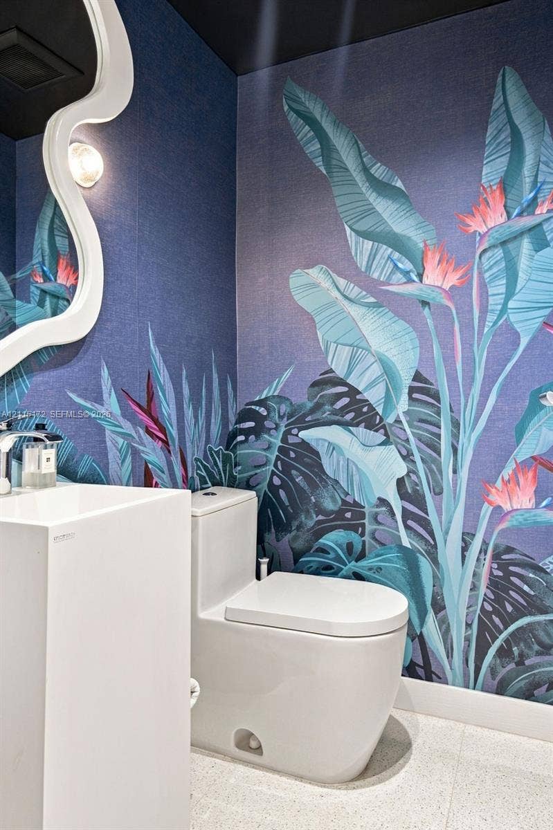 16 Island Avenue, #5C, Miami Beach, FL 33139 Powder room featuring botanical print wall covering, sculptural white pedestal sink with chrome faucet, high-profile dual-flush toilet, and wall-mounted irregular-shaped mirror