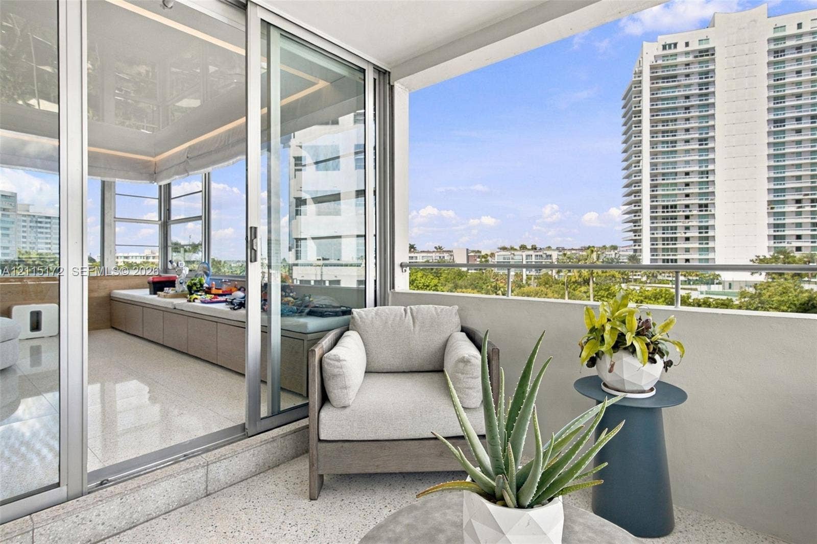 16 Island Avenue, #5C, Miami Beach, FL 33139 Covered balcony with a metal railing and light-colored flooring, accessed via floor-to-ceiling glass sliding doors