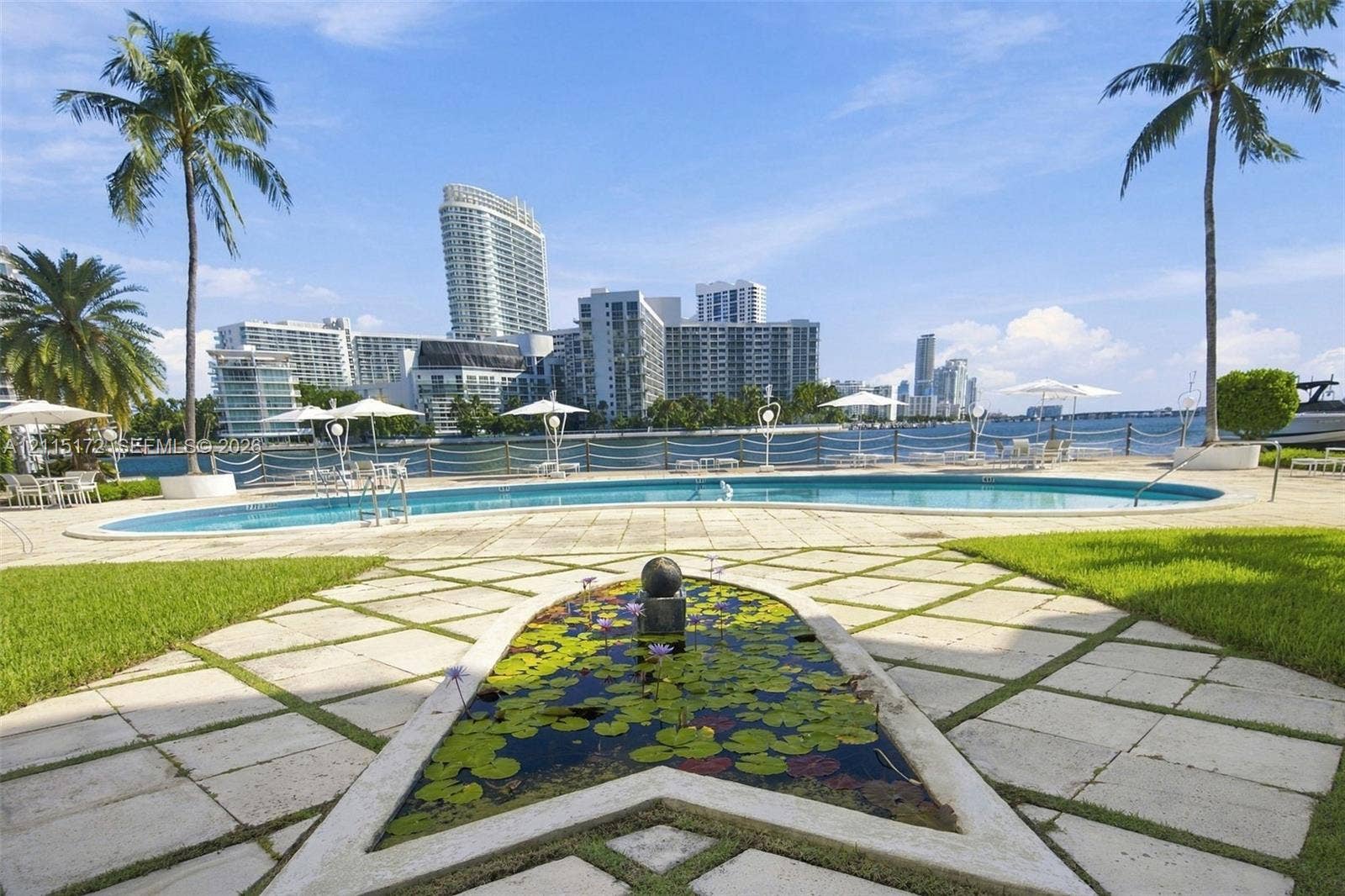 16 Island Avenue, #5C, Miami Beach, FL 33139 Outdoor space featuring a swimming pool, decorative pond with stone border, paved patio, manicured lawn, and perimeter fencing