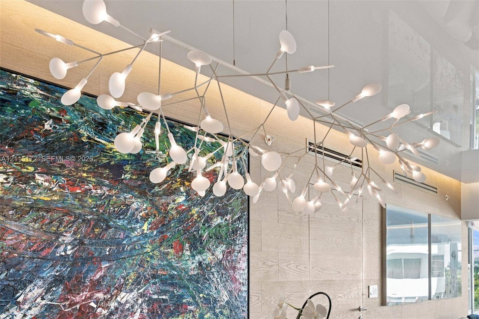 16 Island Avenue, #5C, Miami Beach, FL 33139 Sculptural multi-arm pendant fixture with matte white finish and frosted glass globes, paired with wood-panel feature wall and recessed cove lighting