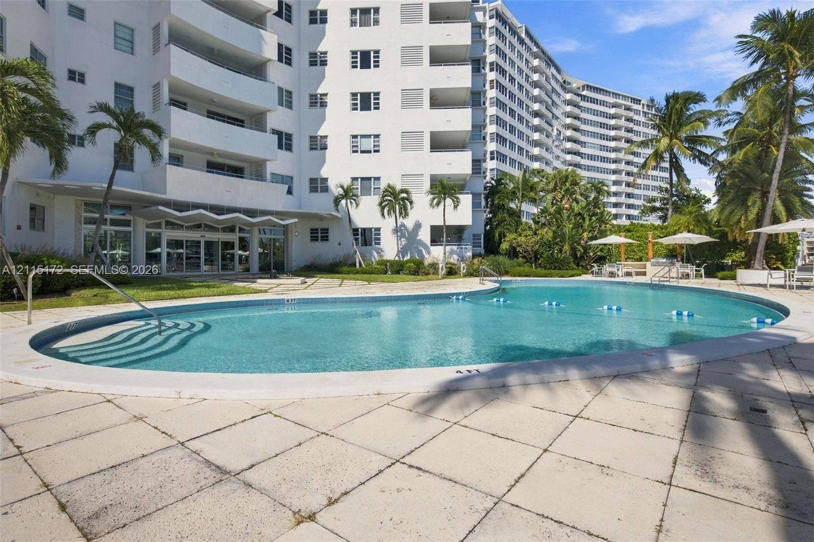 16 Island Avenue, #5C, Miami Beach, FL 33139 Curved outdoor swimming pool with stone-tile decking, mature palm trees, and ground-level balcony access
