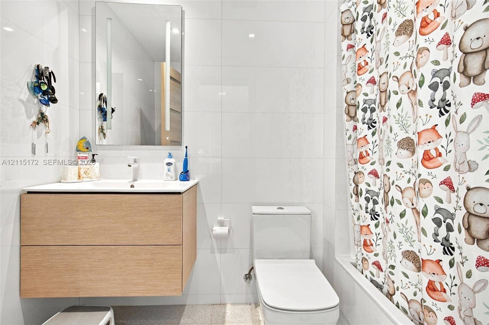 16 Island Avenue, #5C, Miami Beach, FL 33139 Floating vanity with wood-finish cabinetry, integrated rectangular sink, wall-mounted LED-backlit mirror, and full-height white wall tiling