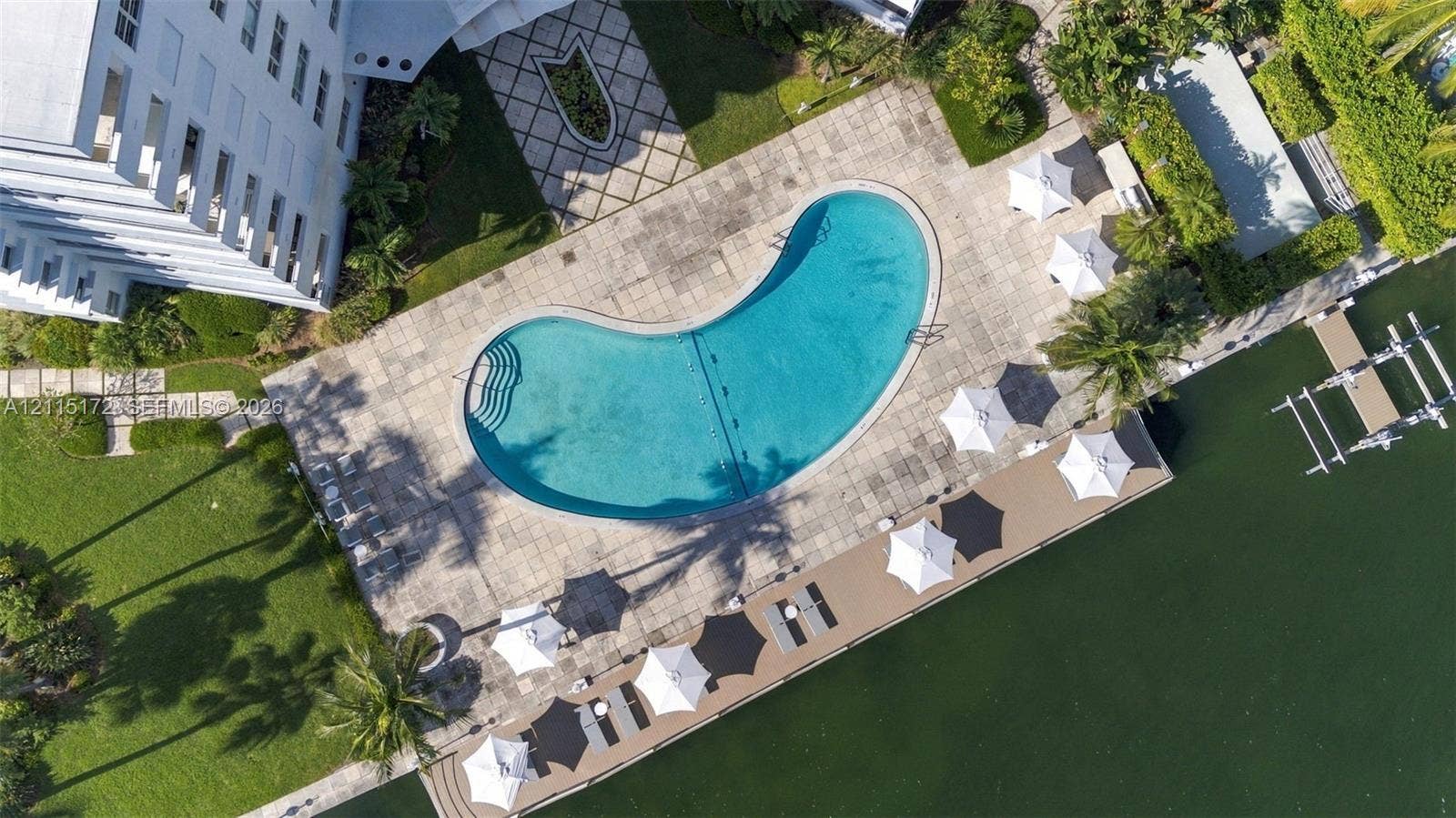 16 Island Avenue, #5C, Miami Beach, FL 33139 Waterfront grounds featuring a kidney-shaped swimming pool, paved stone decking, landscaped lawn areas, and a dedicated boat dock